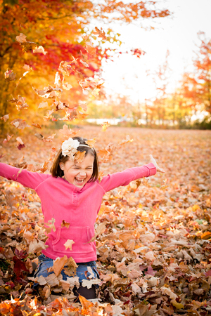 Happy Little Girl Throwing Autumn Leavesの写真素材