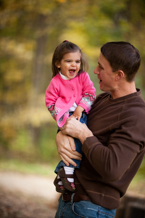 Father and Daughter Laughing in Autumn Parkの写真素材