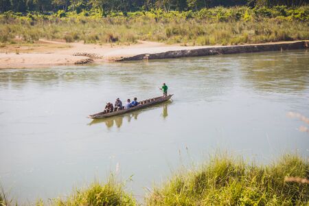 Sauraha,Nepal - Oct 23,2018: Tourist returing from jungle safari on ancient wooden boat in Rapti River,Sauraha.のeditorial素材