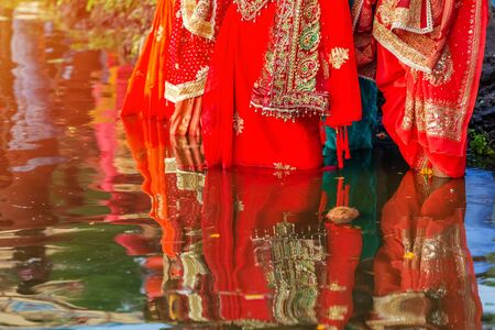 Nepali Hindu woman standing in water with offerings at dusk to pray dipping sun during Chhath Puja festivalの写真素材