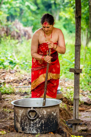 Gorkha,Nepal - June 26,2019: Nepali Brahmin Woman in traditional attire cooking food at wedding ceremony in rural village of Nepal.のeditorial素材