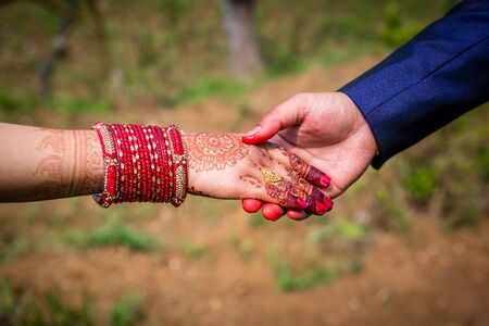 Young adult male groom and female bride holding hands together,Hands of newlywed couple.の写真素材