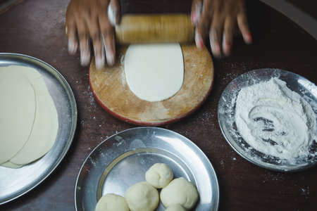 Close up of woman hand rolling dough with rolling pin on kitchen counter tableの写真素材