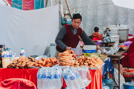 Kathmandu, Nepal - Jan 15, 2023 : Nepali Food Seller arranging foods like; Sel Roti,Fried Fish, Samosa,Momo etc at the food stall in Tudikhel.のeditorial素材