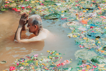 kathmandu, Nepal - April 20, 2023 : Devoted Hindu man taking a holy bath at the pond in Matatirtha...
