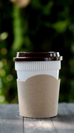 Hot coffee in plastic coffee cup in a garden with space for write wording, plastic cup is an important source of hardly destroyed garbage and lead pollution problem of the worldの写真素材