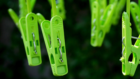 Green clothespins hanging in a garden in strong sunlight environmentの写真素材