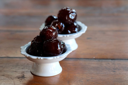 Sweet Jujube or Chinese red date in syrup in white Thai style cup on wood table and space for write...