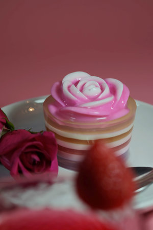 Multilayer sweet coconut fruit jelly with beverage, strawberry and red roses on white plate and pink background and space for write wording for happiness moment. Unhealthy dessert high sugar and fat.の写真素材
