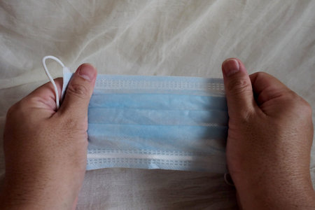 Blue infection preventive face mask in an Asian man hand and space for write wording. Promoting...