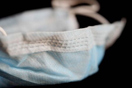 Isolated of used blue infection preventive face mask on black background and space for write wording. Important tools for protecting ourselves from infection in Corona virus crisis 2020. Waste controlの写真素材