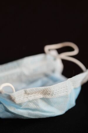 Isolated of used blue infection preventive face mask on black background and space for write wording. Important tools for protecting ourselves from infection in Corona virus crisis 2020. Waste controlの写真素材