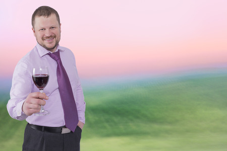Businessman holding glass of wine with sunrise backgroundの写真素材