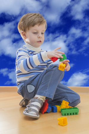 Boy playing with plastic construction with cloud sky in backgroundの写真素材