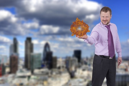 Businessman holding his right hand out, palm up with sphere with modern city in backgroundの写真素材