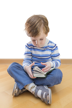 Boy reading book seating on the floor on white backgroundの写真素材