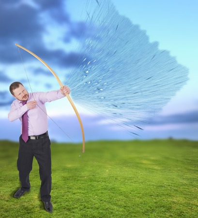 Businessman practicing archery with green field in backgroundの写真素材