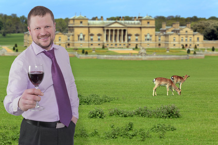 Businessman holding glass of wine with beautiful villa in backgroundの写真素材