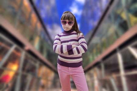Teenage girl in pink wears sunglasses with modern shopping mall in backgroundの写真素材