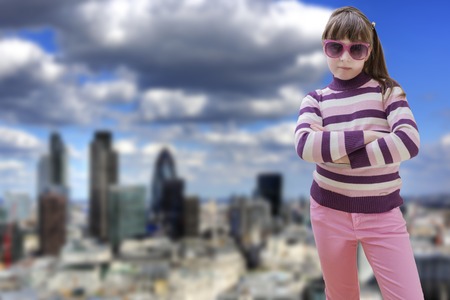 Teenage girl in pink wears sunglasses with modern city in backgroundの写真素材