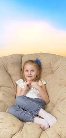 Little girl sitting in armchair with lipstickの写真素材