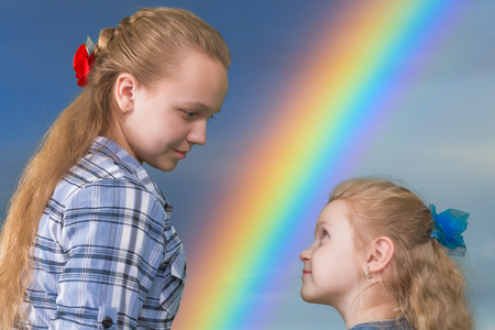 Two sisters watching each other on abstract background with rainbowの写真素材
