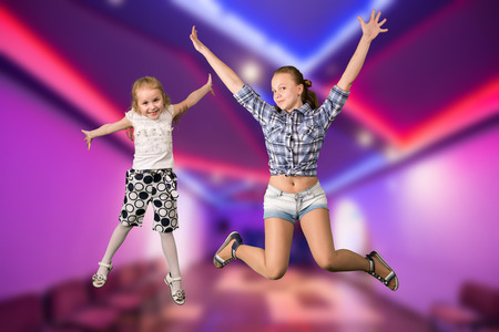 Two girls jumping in dancing hall interiorの写真素材