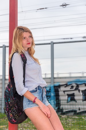Young beautiful woman in shorts with backpack on graffiti backgroundの写真素材