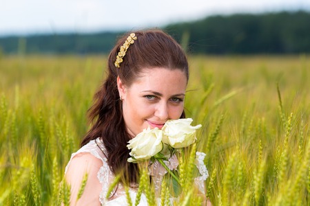 Young woman with white roses in rye fieldの写真素材