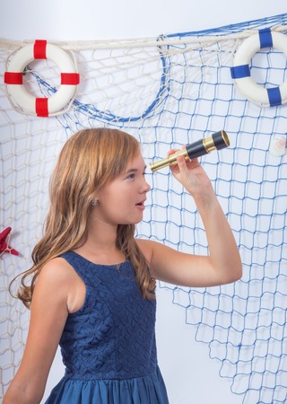 Beautiful teen girl in blue dress looking at telescopeの写真素材