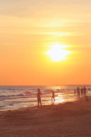 People walking on the beach at sunsetの写真素材