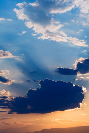 Sky with sun behind the clouds at sunsetの写真素材
