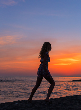 Beautiful young woman on the beach at sunsetの写真素材