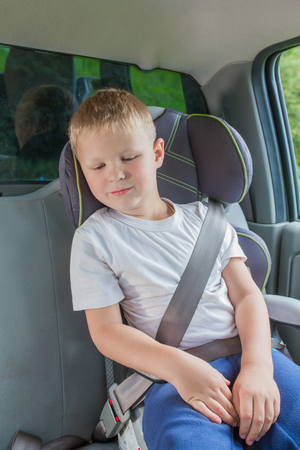 Boy sitting in a car in safety chair fasten seat beltの写真素材