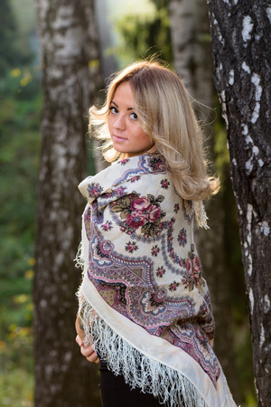 Young attractive woman at traditional shawl near the birch tree.の写真素材