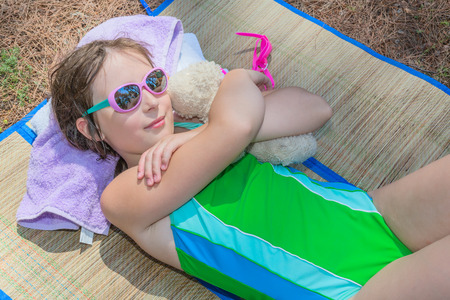 Little girl lying on the plaid embracing plush toyの写真素材