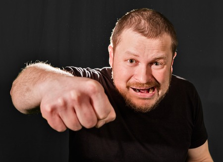 Agressive bully threatens with a fist portrait low keyの写真素材