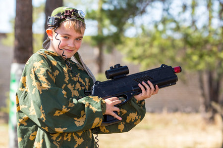 Teen boy with a gun in camouflage playing laser tag