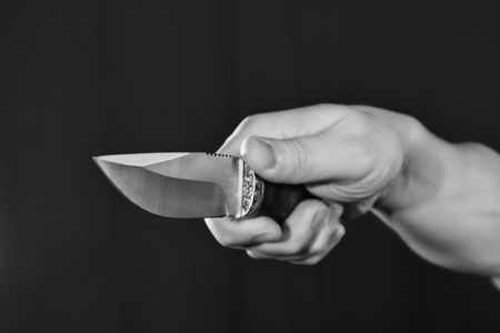 Man's hand holding knife close up view on black backgroundの写真素材