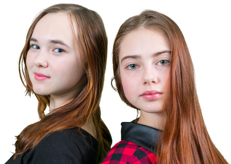 Two beautiful teen girls in red and black clothes standing on white backgroundの写真素材