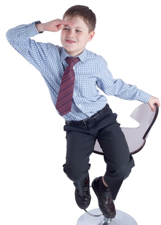 Young schoolboy in school uniform sitting an watching ahead on white backgroundの写真素材