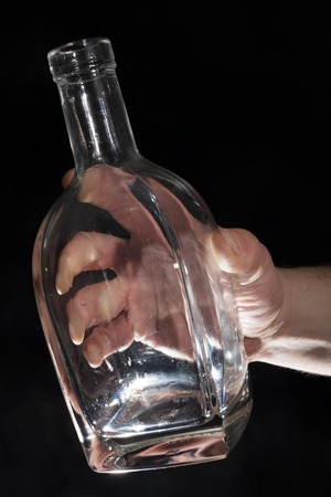 Mans hand holding empty bottle of alcoholの写真素材