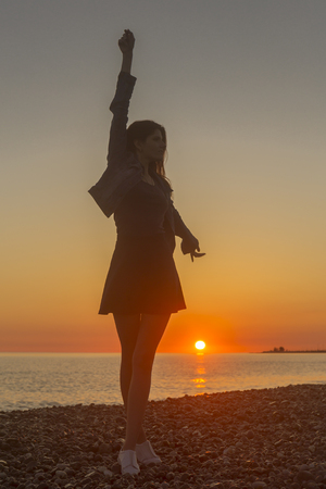 Young attractive woman on the beach at sunset timeの写真素材