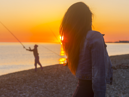Young attractive woman on the beach at sunset time in backlight sceneの写真素材