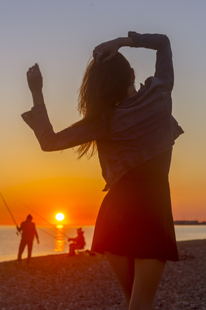 Young attractive woman on the beach at sunset time in backlight sceneの写真素材