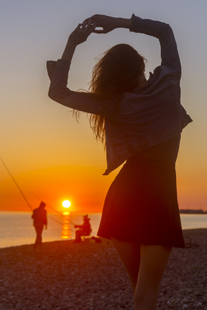 Young attractive woman on the beach at sunset time in backlight sceneの写真素材
