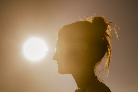 Young attractive woman on the beach at sunset drinking from glassの写真素材