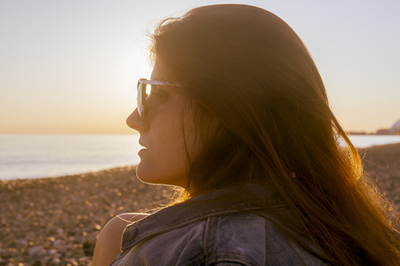 Young attractive woman on the beach at sunset timeの写真素材