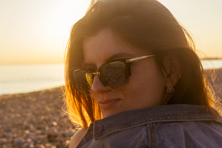 Young attractive woman on the beach at sunset timeの写真素材