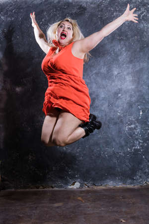 Attractive plump woman in red dress jumpingの写真素材